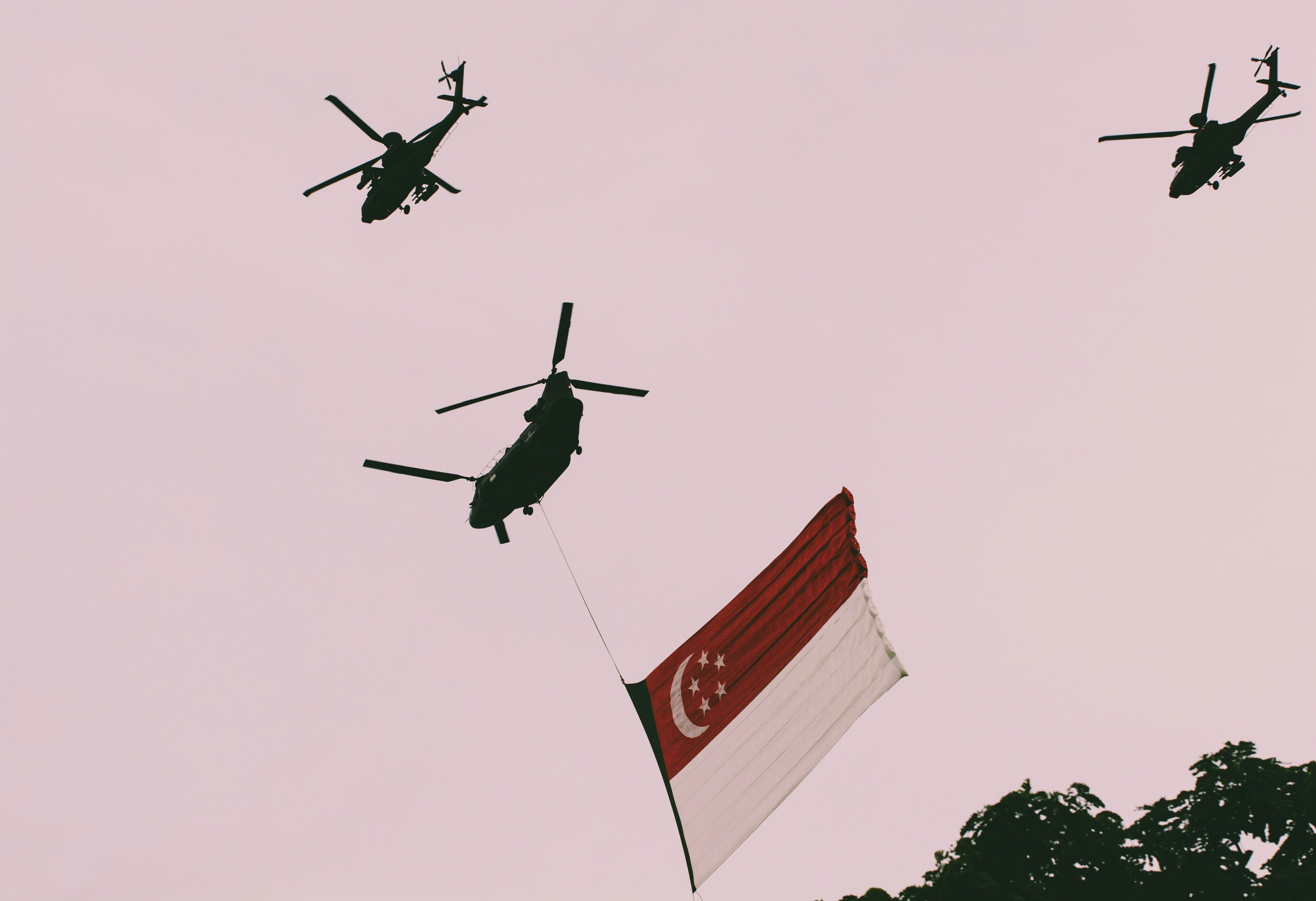 Helicopters carrying the Singapore flag during a flypast